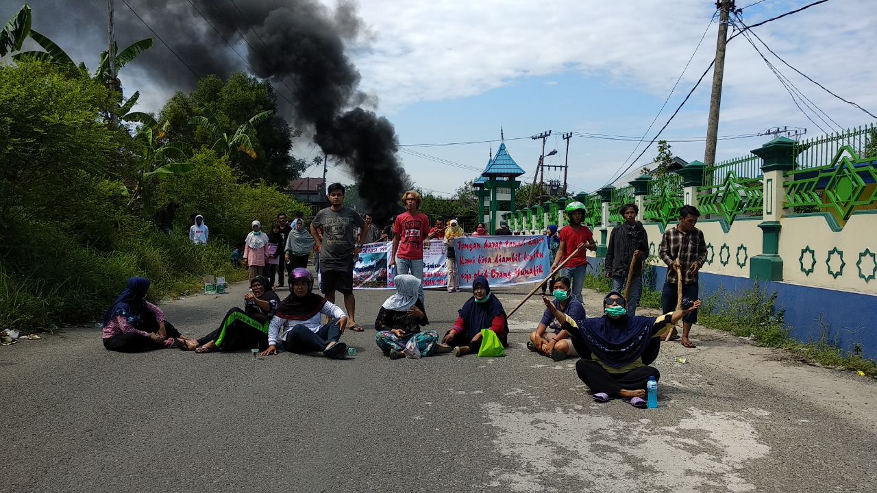 warga menghadang petugas dengan cara memblokir jalan.
