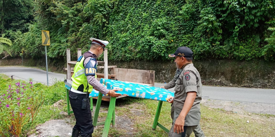 Polisi lalu lintas bersama Sat Pol PP Kabupaten Limapuluh Kota, Sumatera Barat, bahu membahu memindahkan peralatan dagang PKL di Jembatan Layang Kelok 9 (Sembilan). Photo : tanharimage.