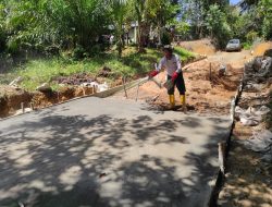 Anggota satgas TMMD melakukan penaburan semen untuk lapis atas jalan rambat beton.