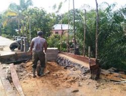 Anggota satgas TMMD menimbun pinggiran jembatan menggunakan pasir