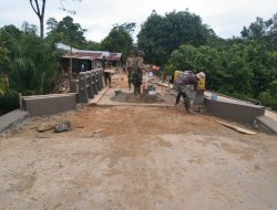 Anggota satgas TMMD plaster tepian jembatan beton yang selesai di bangun