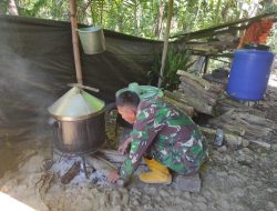 Anggota satgas TMMD memasak dengan cara tradisional menghilangkan kayu bakar.