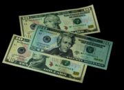 High angle view of US 10 and 20 dollar bills on a black background, emphasizing finance and currency themes.