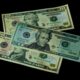 High angle view of US 10 and 20 dollar bills on a black background, emphasizing finance and currency themes.